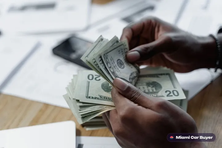 Hand counting cash dollar bills, representing cash-on-the-spot payment for cars in Miami